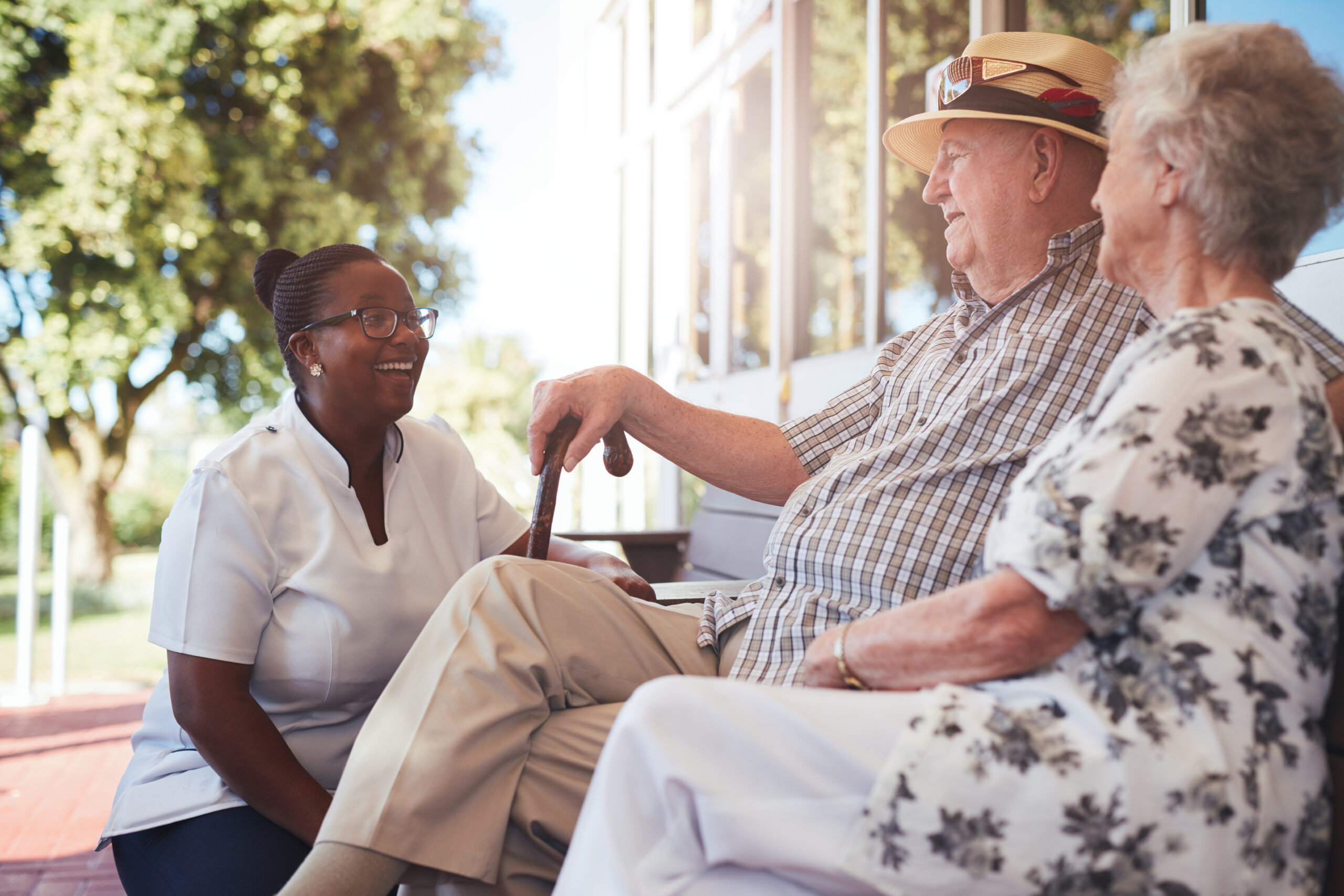 senior couple with caregiver sitting outside