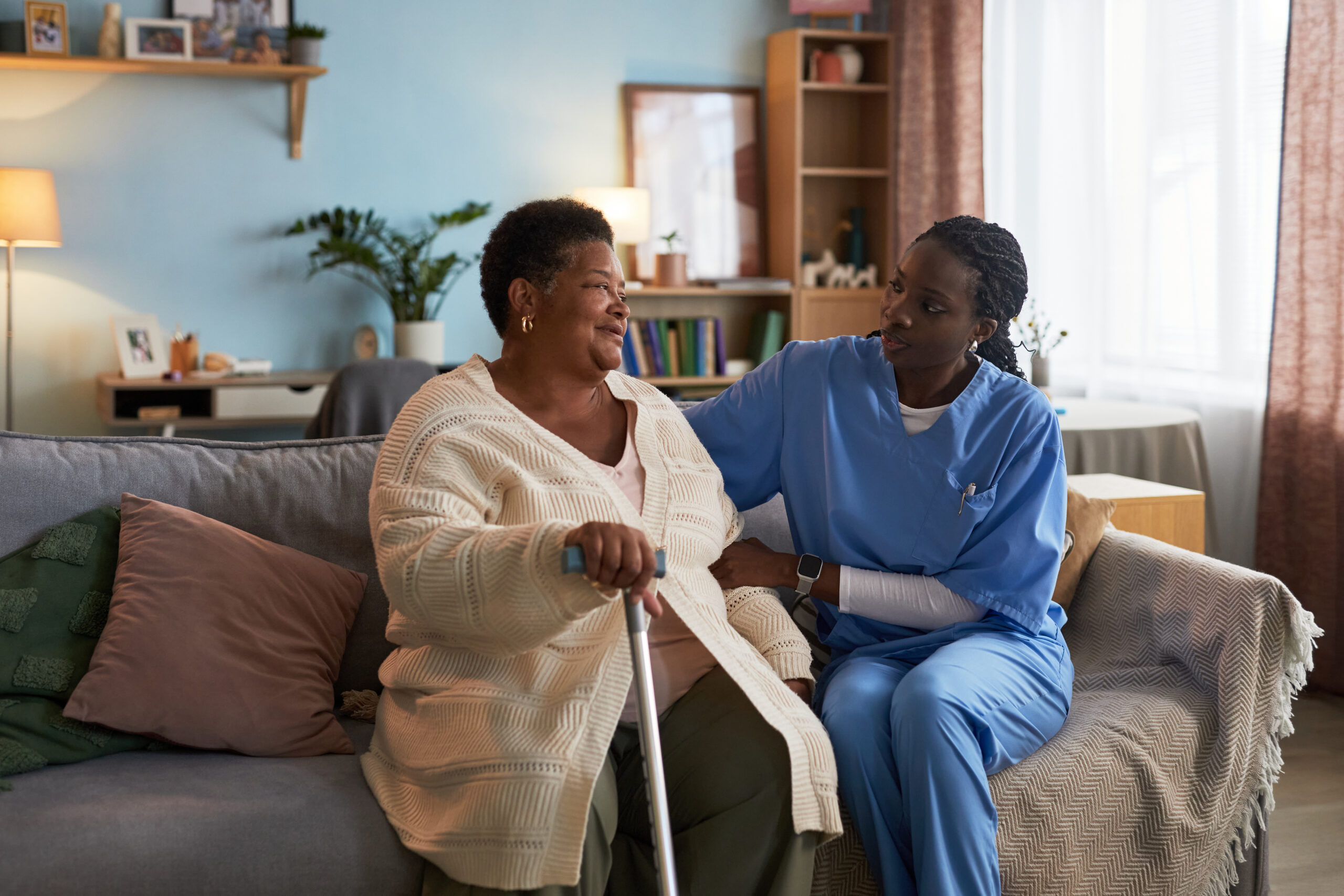 middle aged black woman sitting with cane talking to young nurse